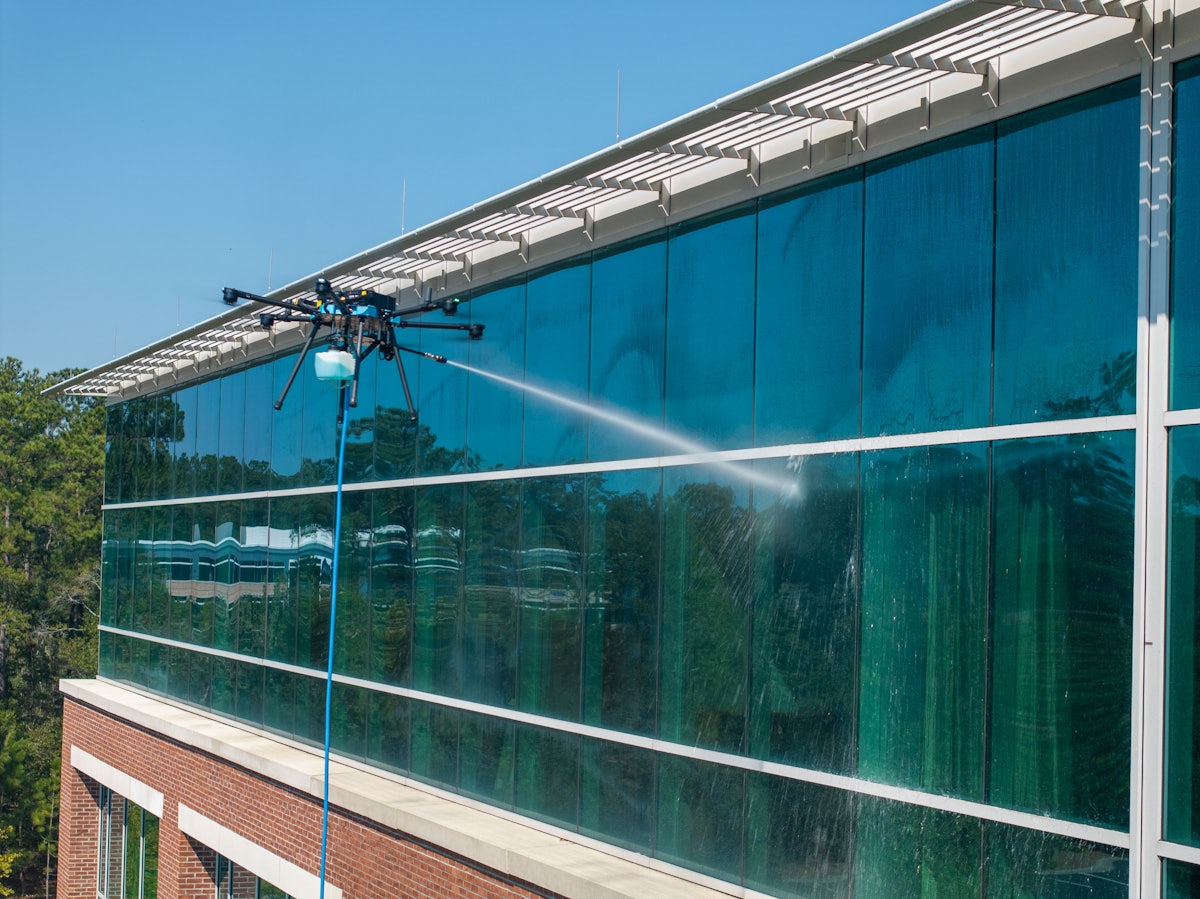 Cleaning drone rinsing a large glass facade wall