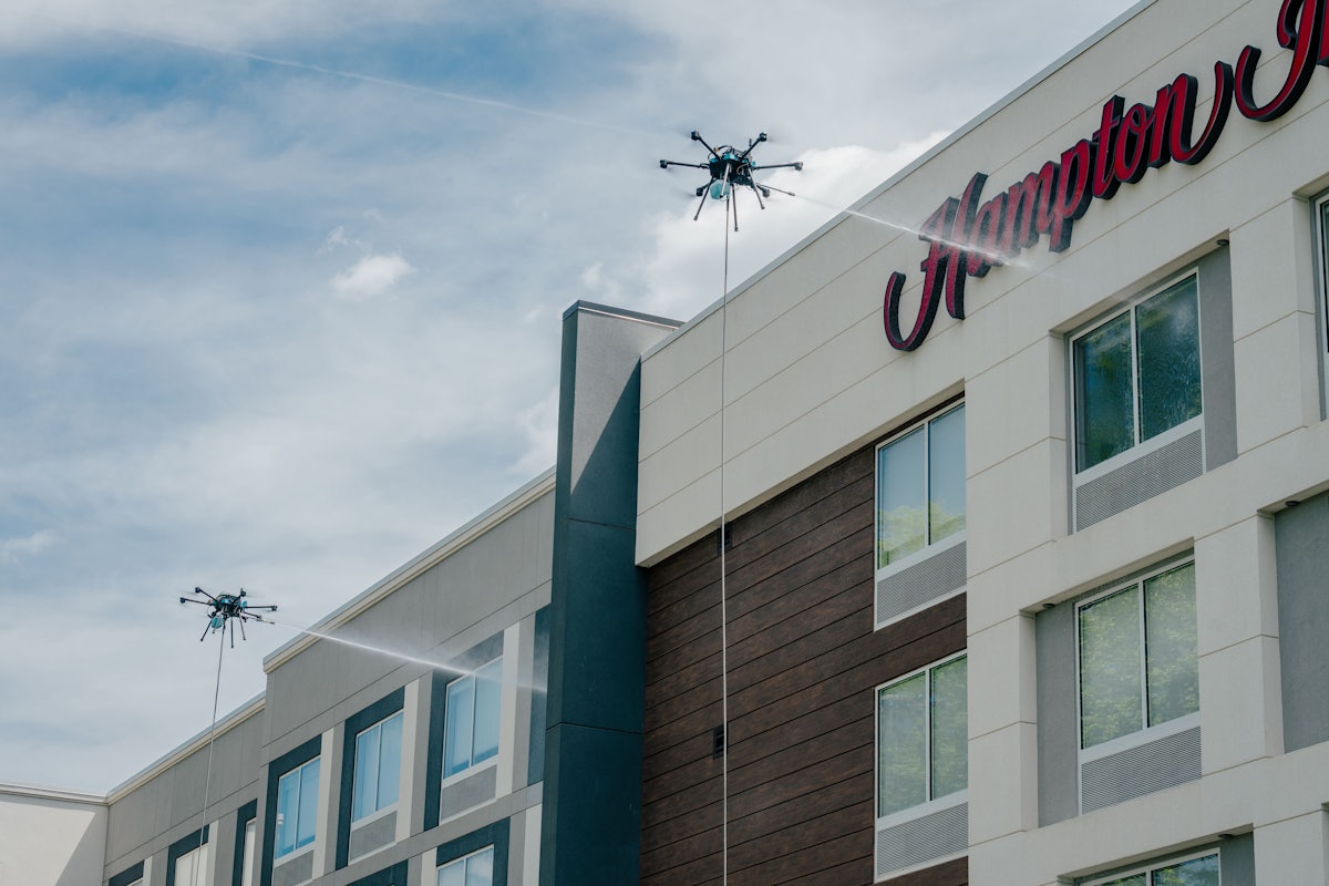 Two cleaning drones washing the upper facade of a hotel building