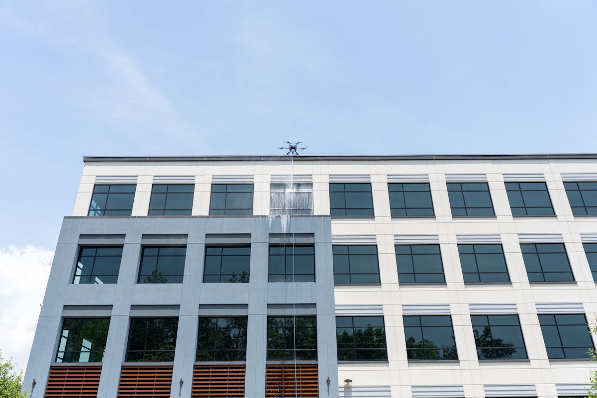 Cleaning drone working the exterior wall of a large low-rise commercial building