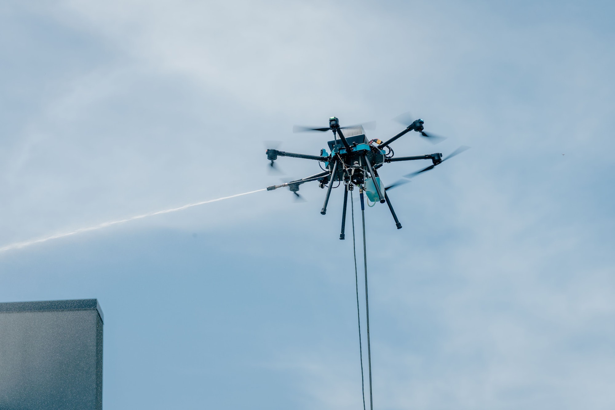 Sherpa cleaning drone spraying water high on a commercial building